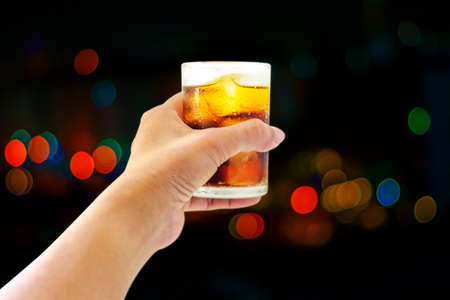 Glass of whiskey drink with ice cube Bokeh background
