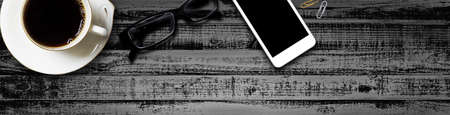 Hot coffee cup of coffee and mobile, glasses, on black wood table top view, Mock up banner for adding your text or design - Web Bannerの写真素材