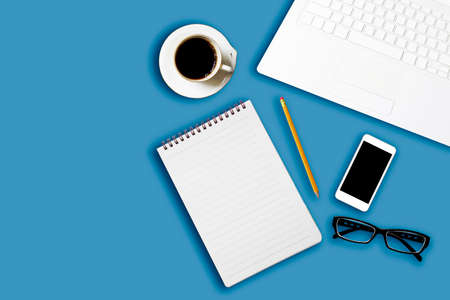 Flay lay, Top view office table desk with smartphone, coffee, pencil, leaves with copy space blue...