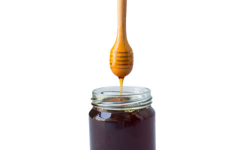 Honey in a glass jar with honey dipper on rustic wooden table backgroundの写真素材