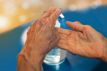 Close up hands of asian senior woman using alcohol gel for hands washing, with hand sanitizer to...