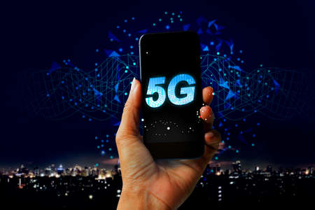 5G network digital hologram and internet of things on city background - Hand holding mobile phone concept of future technology 5G networkの写真素材