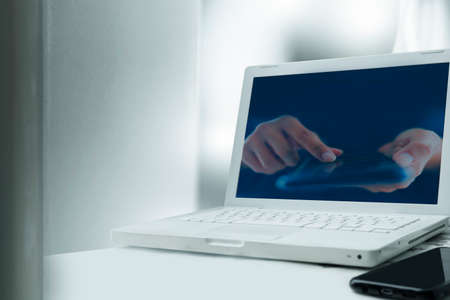 White laptop with screen computer, person use mobile hands holding and touch screen to communicateの写真素材