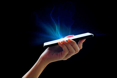Hand holding mobile phone blue light effect on black backgroundの写真素材