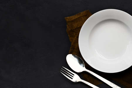 White plate and spoon, fork empty on dark stone table backgroundの写真素材