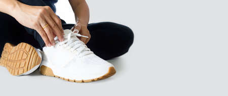 Woman tying shoelaces before exercising with copy space background - Horizontal photo banner for...