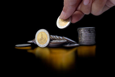 Pile of coin golden and and hand holding coin with golden shadow on dark background - Saving money...