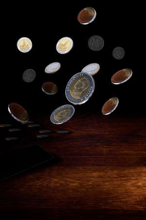 Coins baht falling from the top with shadow isolated on dark wood background - Saving money conceptの写真素材