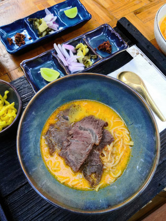 Thai noodle soup with beef in a bowl on wooden tableの写真素材