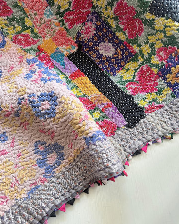 Colorful hand knitted blankets on a white wooden table, close up