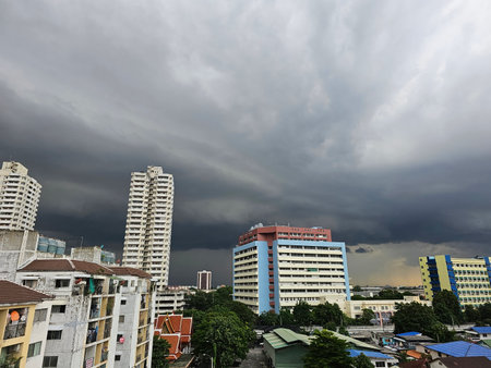 A stormy sky looms over a cityscape, with dark clouds contrasting against modern buildings, hinting at impending rain.の写真素材