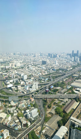 A panoramic cityscape showcasing urban structures, roads, and a hazy skyline under clear conditions.