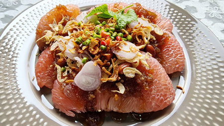 A vibrant citrus salad featuring fresh pink segments, garnished with herbs and crispy onions, perfect as a refreshing appetizer or light meal.の写真素材