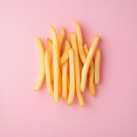 A delightful arrangement of crispy golden fries set against a playful pink background, perfect for...