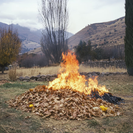 A vibrant scene of autumn leaves burning on a pile in a serene mountain landscape. The warm colors of the fire contrast with the surrounding nature, creating a beautiful outdoor view.の写真素材