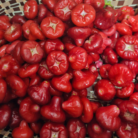 A vibrant collection of fresh red fruits displayed in a woven basket, showcasing their rich colors...