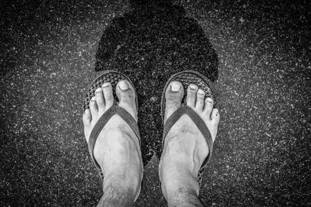 Black and white of Top view feet in sandals selfie shot of asian men legs with wet streetの写真素材