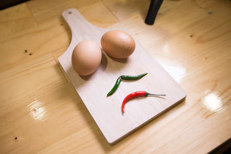 Low key- Eggs and chili scowl emotion on the wood.の写真素材