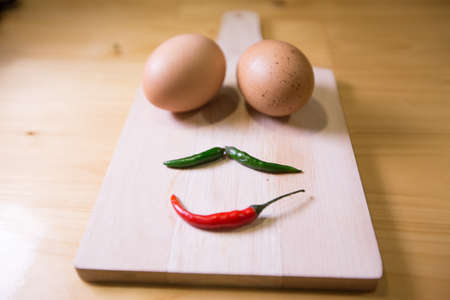 Low key- Eggs and chili scowl emotion on the wood.の写真素材