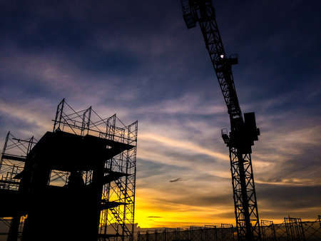 Silhouette of scaffolding in the construction site before to night time or sunset time. worker empty. Building under construction and the construction crane or  power craneの写真素材