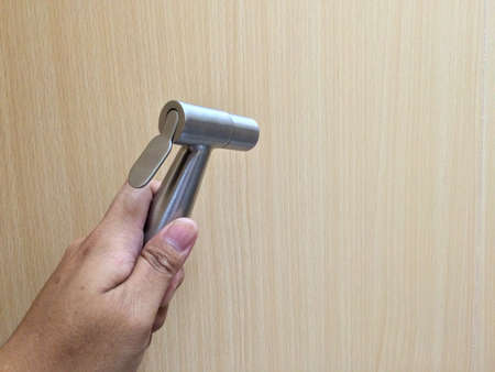 Hand using a bidet shower on wooden wall in toilet(restroom)の写真素材