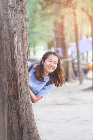 young woman standing behide the tree at relax pose or freedom pose or chill pose on the beach in holiday.の写真素材