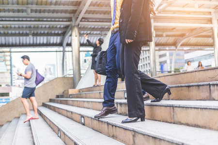 Couple Businessman and Business woman up the stairs in a rush hour to work.の写真素材