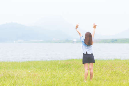 Young woman standing at relax pose or freedom pose or chill pose on the meadow during sunrise at morning. Riverside.の写真素材