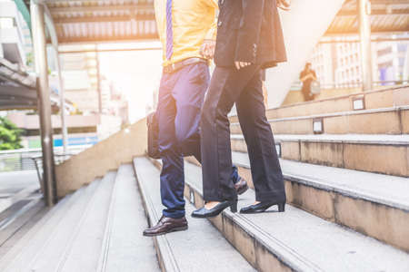 Couple Businessman and Business woman up the stairs in a rush hour to work.の写真素材