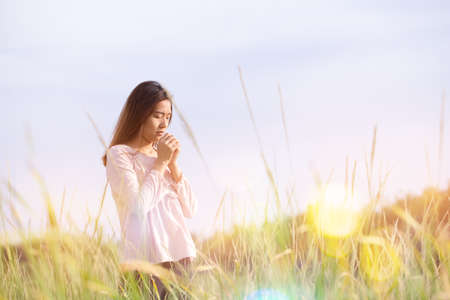 Young woman standing at relax pose or freedom pose or chill pose on the meadow during sunrise at morning.の写真素材