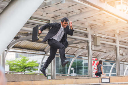 Businessman  holding bag and running rapidly to airport in formal suit. In rush hour at stairway in city. Business in the city concept.の写真素材