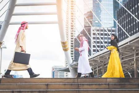 Two Young Muslim business man holding smart phone and bag and walking rapidly to airport and Young...