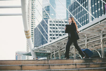 Businesswoman dragging a suitcase. And walking through the corridor during rush hour in the city.の写真素材