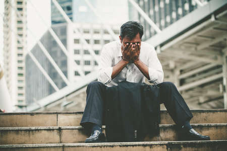 Tired or stressed businessman sitting on the walkway in the city after his work. Image of Stressed businessman concept.の写真素材