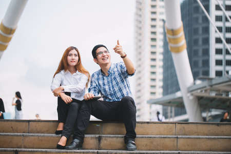 Young Businessman and businesswoman using digital tablet with colleagues in background at walkway at city.technology and teamwork conceptの写真素材