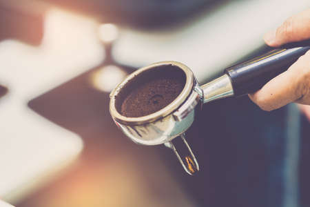 Hand of barista using tamper with ground coffee into portafilter in cafe for prepare to make espresso coffee.の写真素材