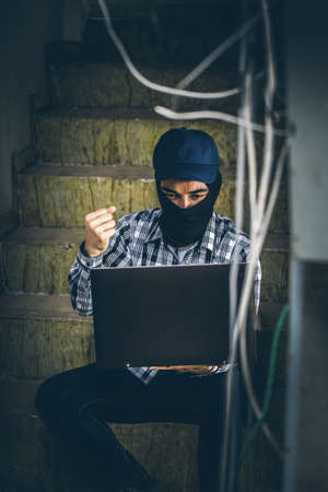 computer hacker of terrorist stealing information with laptop in abandoned building. Low key photo.の写真素材