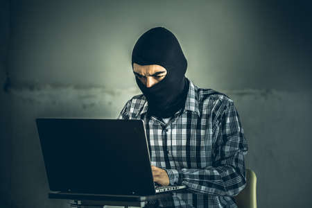 computer hacker of terrorist stealing information with laptop in abandoned building. Low key photo.