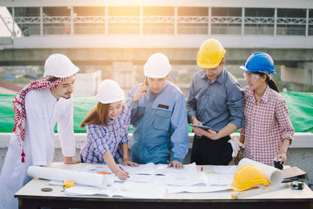 Business and Engineer working concept: Muslim Businessman, Engineer, Foreman and Worker discussing about plan of building site construction progression with layout paper at deck of their building.の写真素材