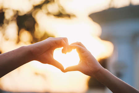 Heart shape made with hands of couple sunset background. Love symbol concept.の写真素材