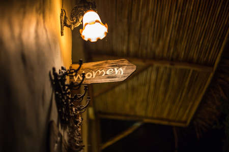 Public Women toilet sign on old wooden with light at night time.の写真素材