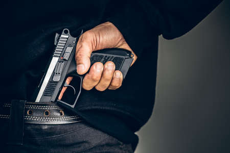 Robber pulls out a gun tucked in his jean. criminal and robbery concept.の写真素材