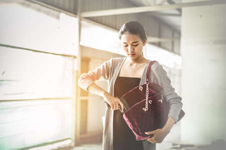 Woman pulls a gun from her swanky purse. Conceal carry weapon for protection themselves concept. Selective focus to gun.の写真素材