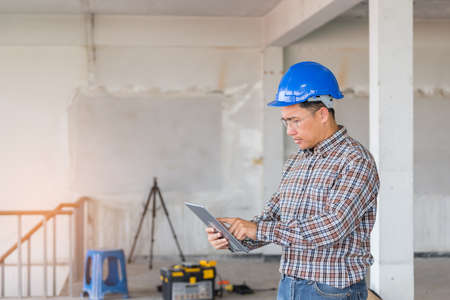Portrait of confident foreman holding tablet with safety helmet on old buildings in their job site.