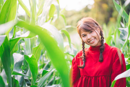 Young Women braided hair wearing a red shirt standing in a cornfield. Hipster concept.の写真素材