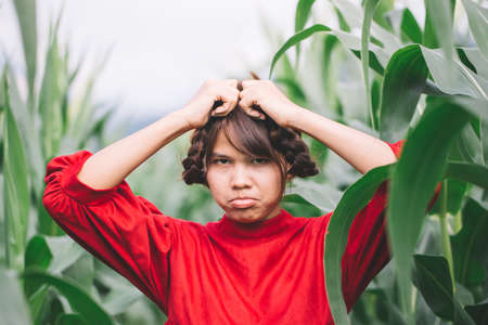 Young Women braided hair wearing a red shirt standing in a cornfield. Hipster concept.の写真素材