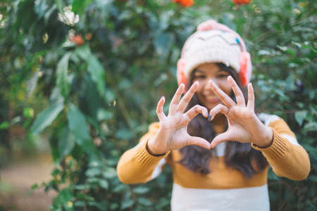 Heart shape made with hands of young women wearing a sweater in  green natural background. Love symbol concept.の写真素材