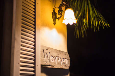 Public Women toilet sign on old wooden with light at night time.の写真素材