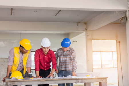 Foreman, labor and engineer as discussing about their project with blueprint with safety helmet on table at old buildings in their job site.の写真素材