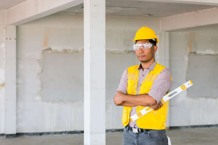 Portrait of confident Labor standing with safety helmet and level measurement on old buildings in their job site.の写真素材